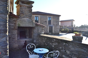 Un edificio de piedra con un pequeño patio que tiene una mesa redonda y sillas.