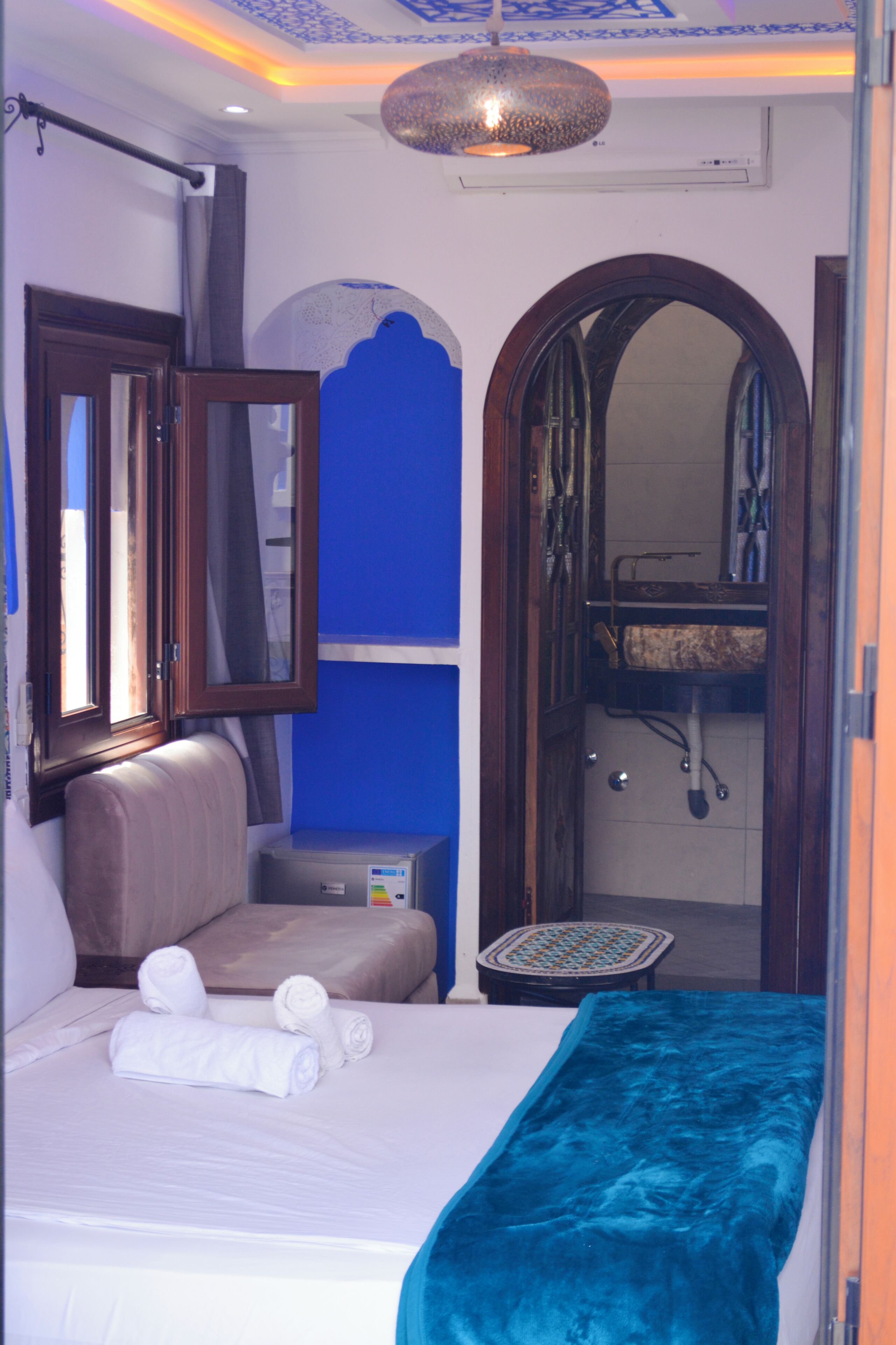 A hotel room with a bed, a bathroom with a sink, and a mirror.