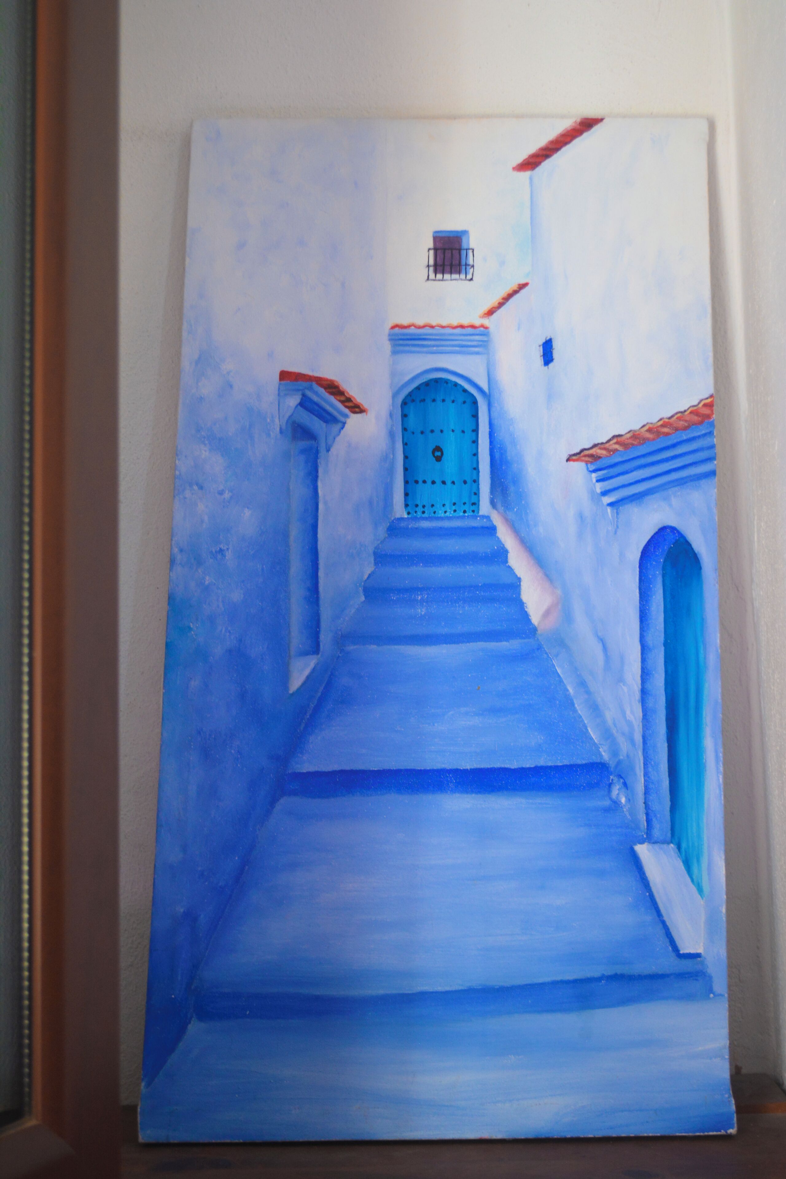 Un tableau représentant un bâtiment bleu avec une porte et des marches.