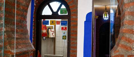 A hotel entrance with a brick archway, a sign indicating a 9.0 rating, and various logos of travel agencies and hotels.