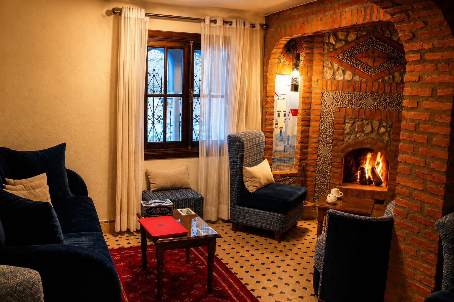 A cozy room with a fireplace, a sofa, a chair, and a small table with a red book.