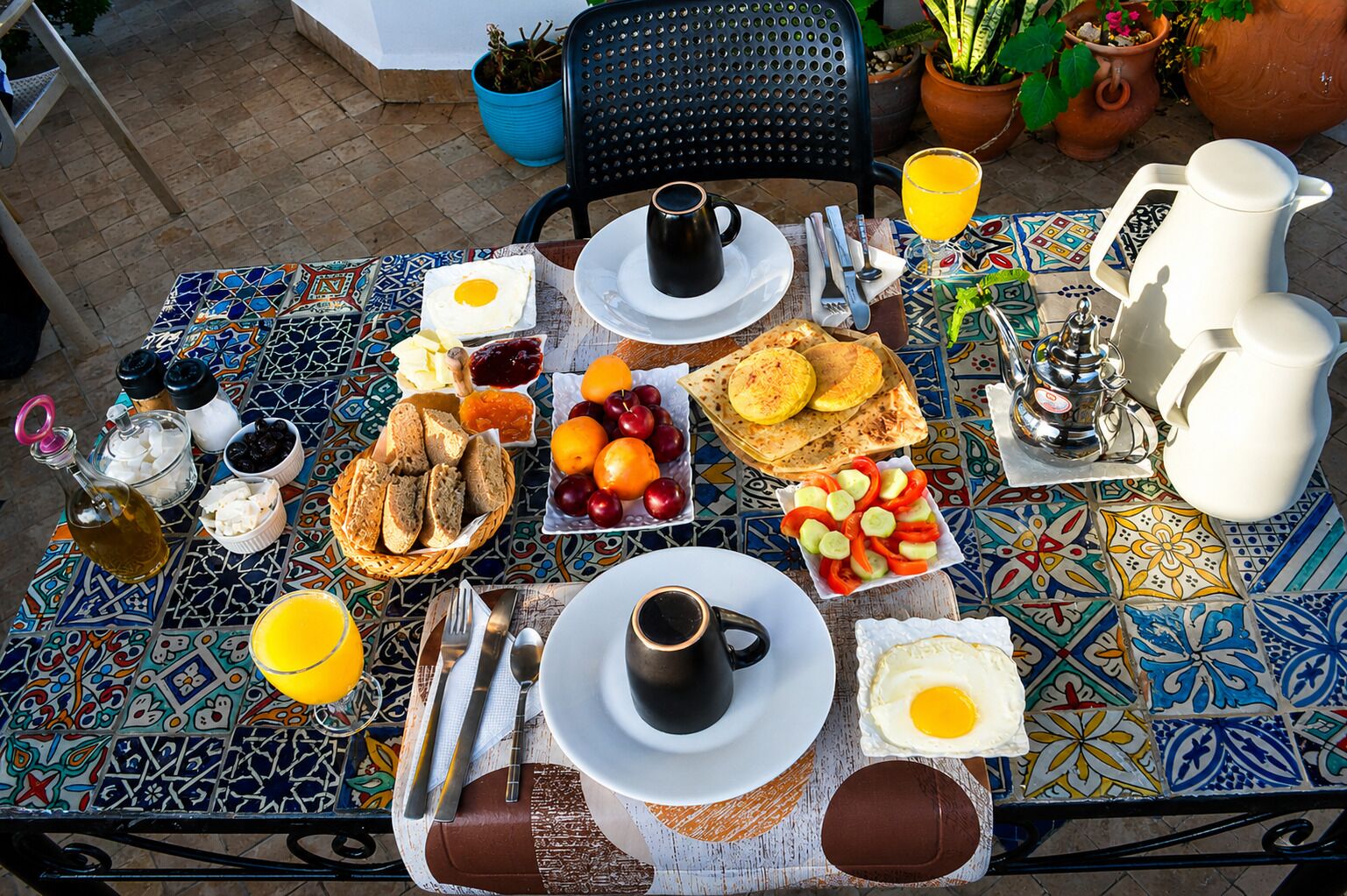 Una mesa de desayuno con diferentes alimentos, bebidas y una cafetera.