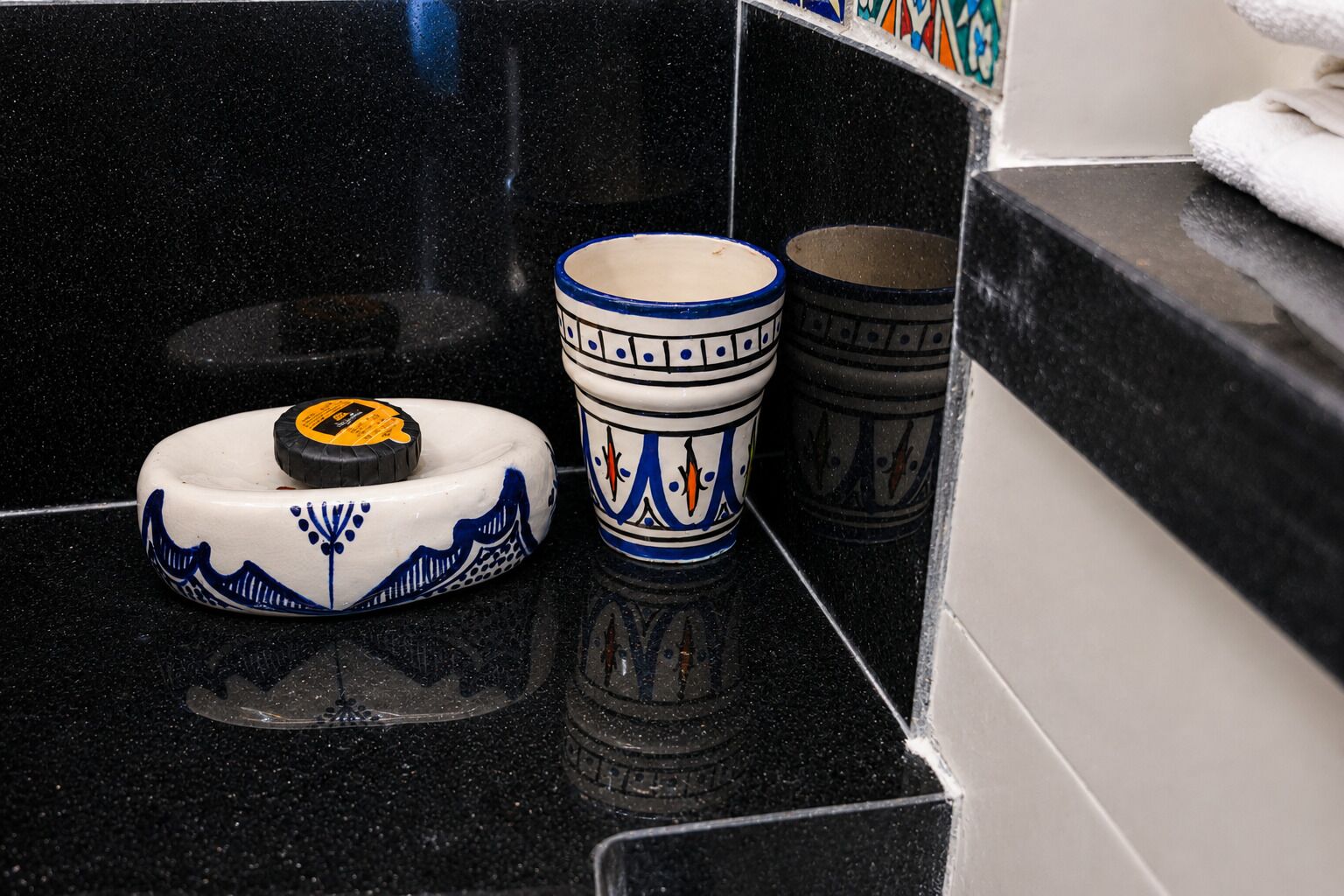 Una encimera negra con un plato, una taza y un recipiente de cerámica blanca y azul.