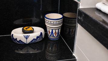 Una encimera negra con un plato, una taza y un recipiente de cerámica blanca y azul.