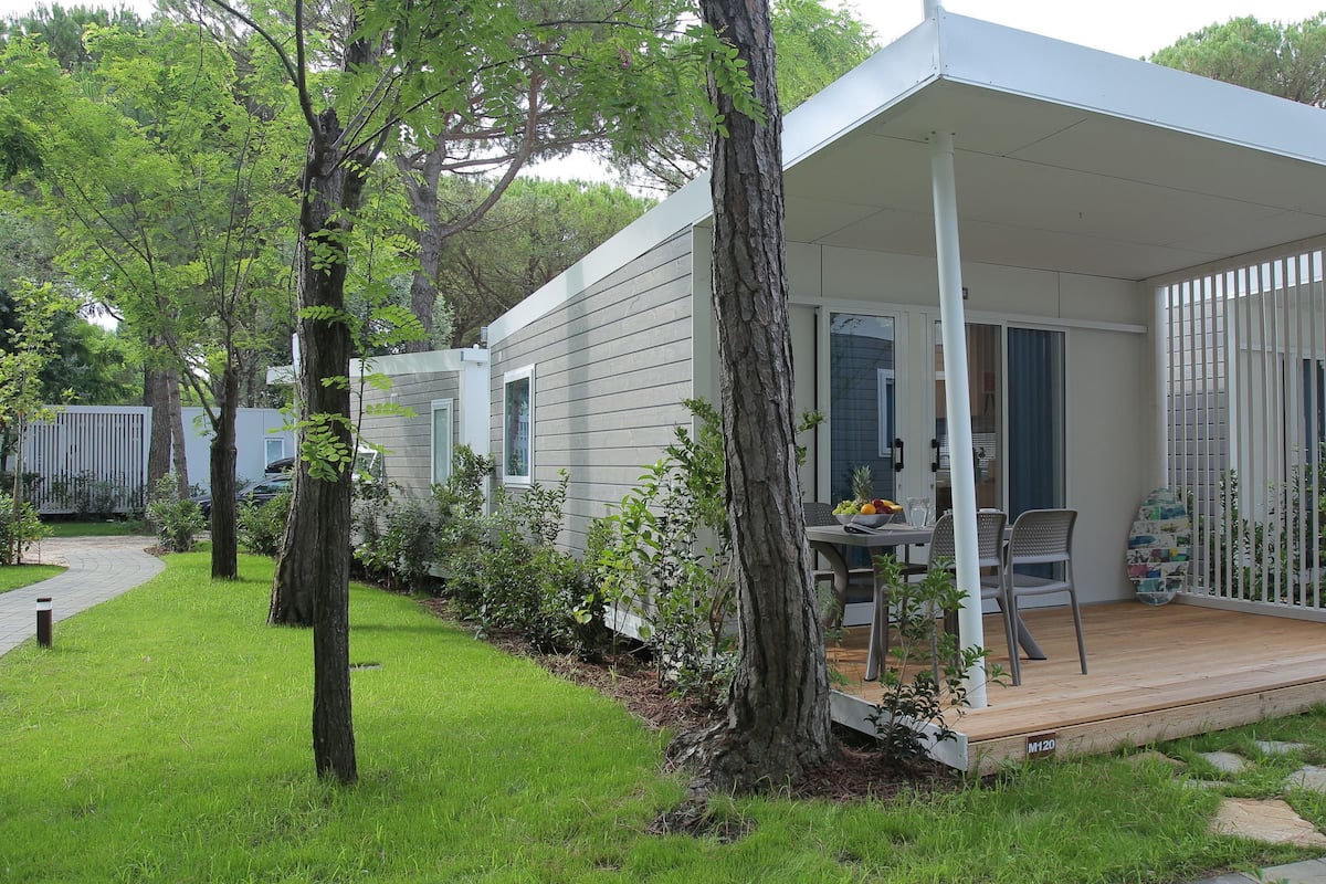 A small, single-story house with a covered patio area, a dining table, and chairs.