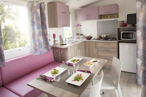A modern kitchen with pink cabinets, a dining table set for four, and a built-in oven.
