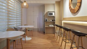 A modern kitchen with a microwave, wooden stools, and a round mirror on the wall. - Hotel Berri Versalles (Renteria)