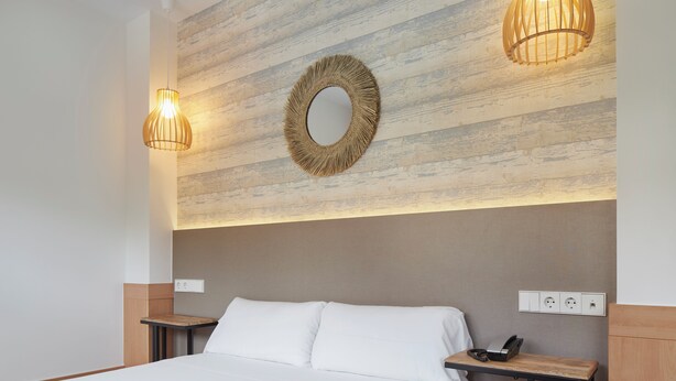 A hotel room with a bed, bedside tables, a wall-mounted mirror, and two pendant lights. - Hotel Berri Versalles (Renteria)
