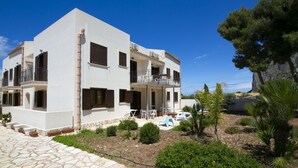 A two-story building with a balcony, outdoor seating area, and a stone-paved courtyard.