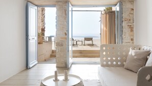 A modern living room with a large window, a sofa, and a coffee table. - Calme Boutique Hotel Paros- Adults Only (Paros)