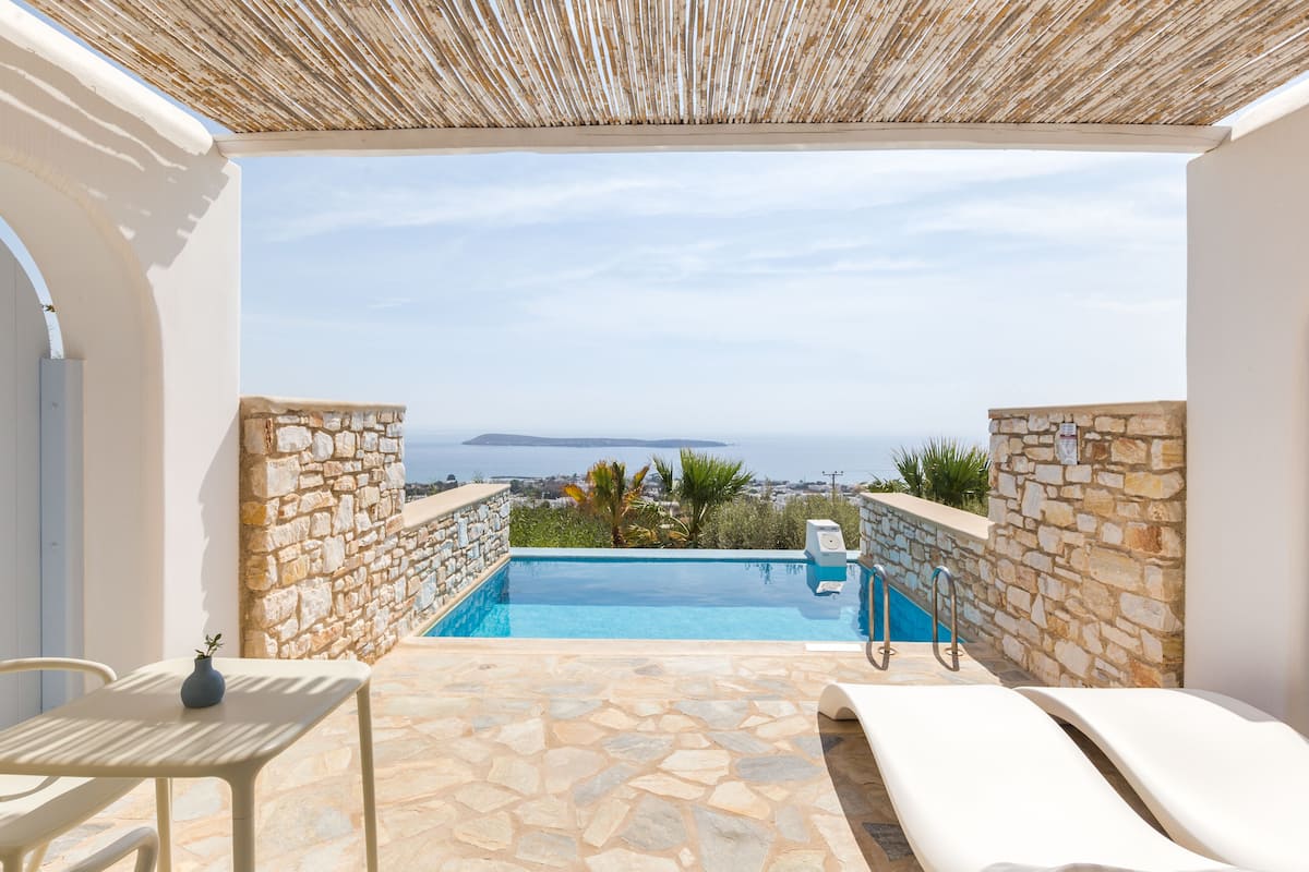 Piscina en la azotea con paredes de piedra y vistas al mar.