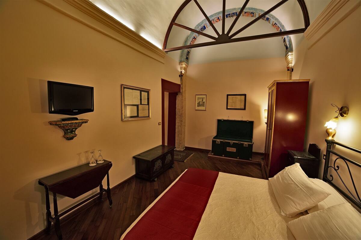 Una habitación de hotel con cama, televisión, una mesita y escritorio.