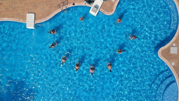 An aerial view of a swimming pool with multiple lanes, lounge chairs, and a lifeguard stand. - Hotel Palm Beach (Pointe-Noire)