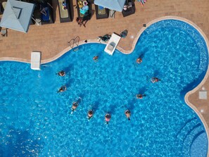 An aerial view of a swimming pool with multiple lanes, lounge chairs, and a lifeguard stand. - Hotel Palm Beach (Pointe-Noire)
