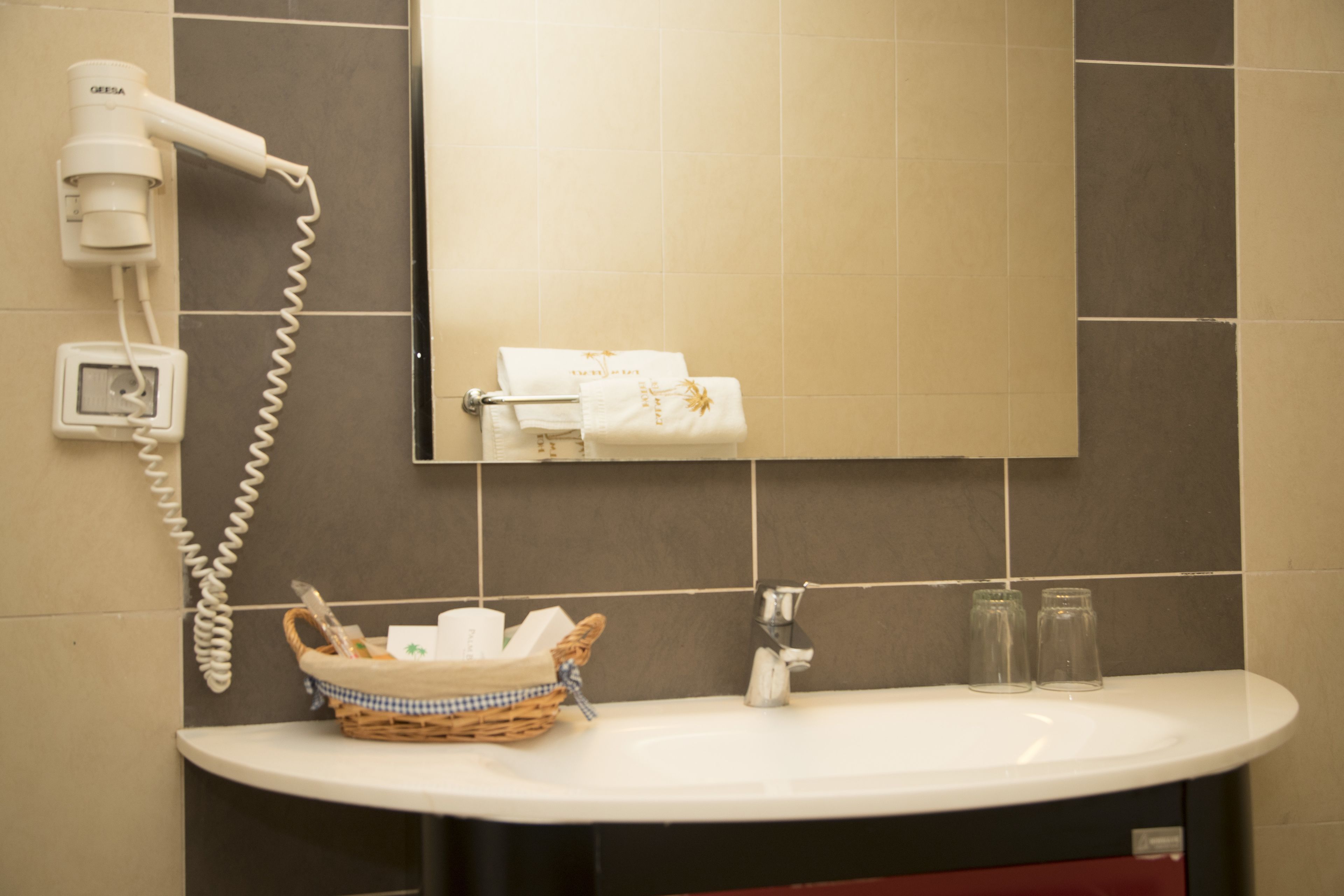 A bathroom with a white sink, a hairdryer, a mirror, and a towel rack.