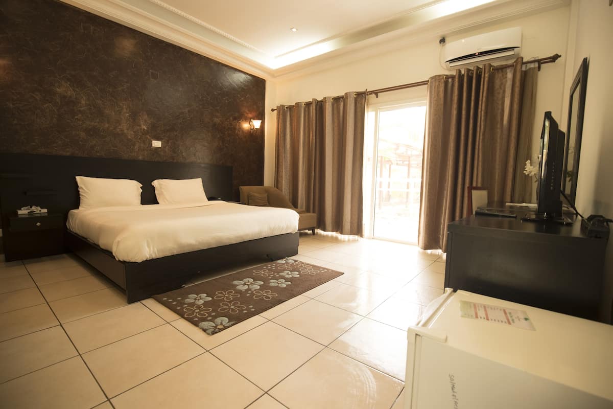 Habitación de hotel con una cama grande, un escritorio, televisión y vistas al exterior.