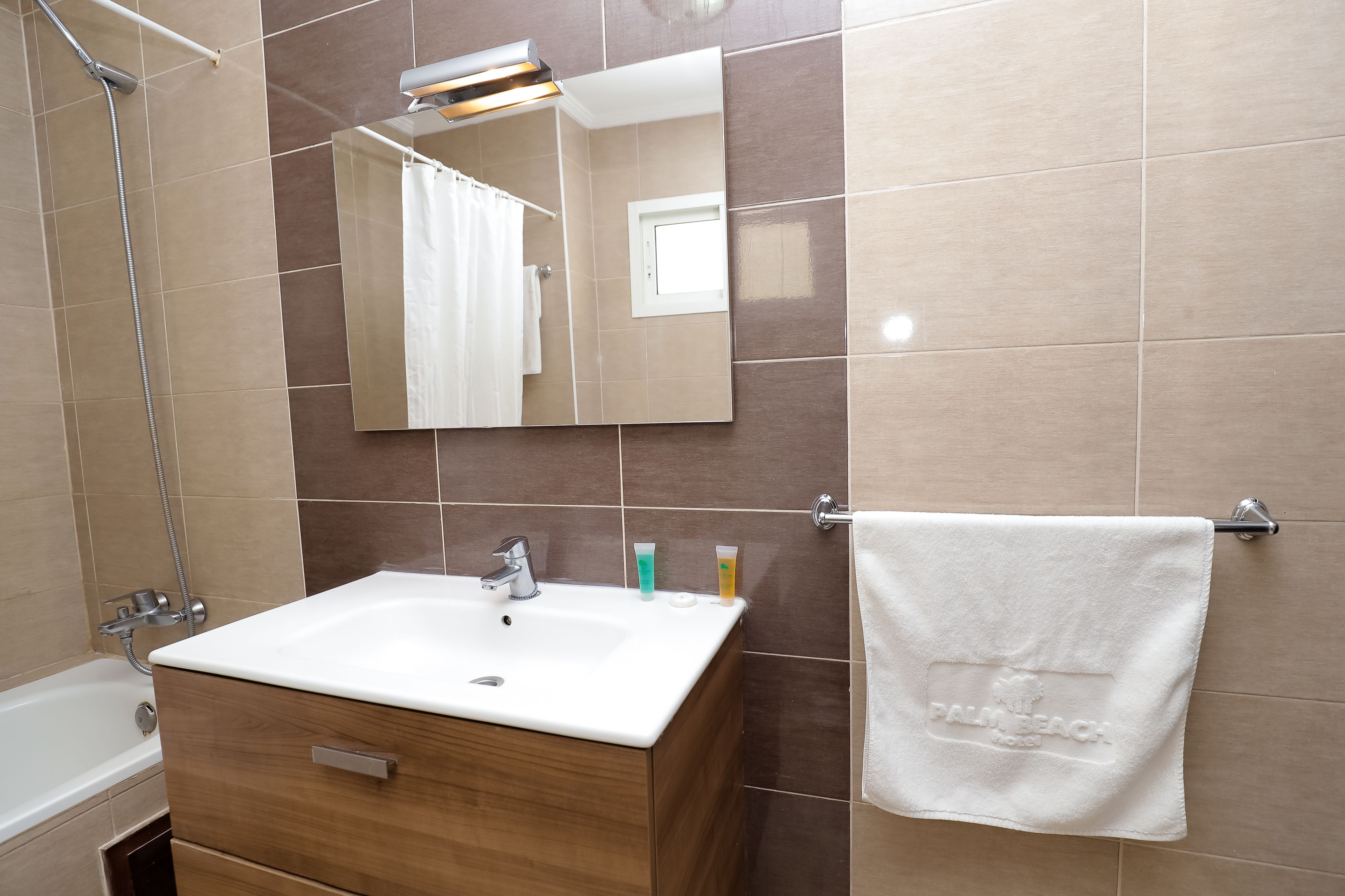 A bathroom with a white sink, wooden vanity, and a mirror.