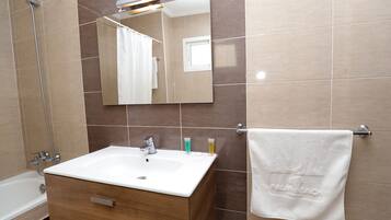 A bathroom with a white sink, wooden vanity, and a mirror.