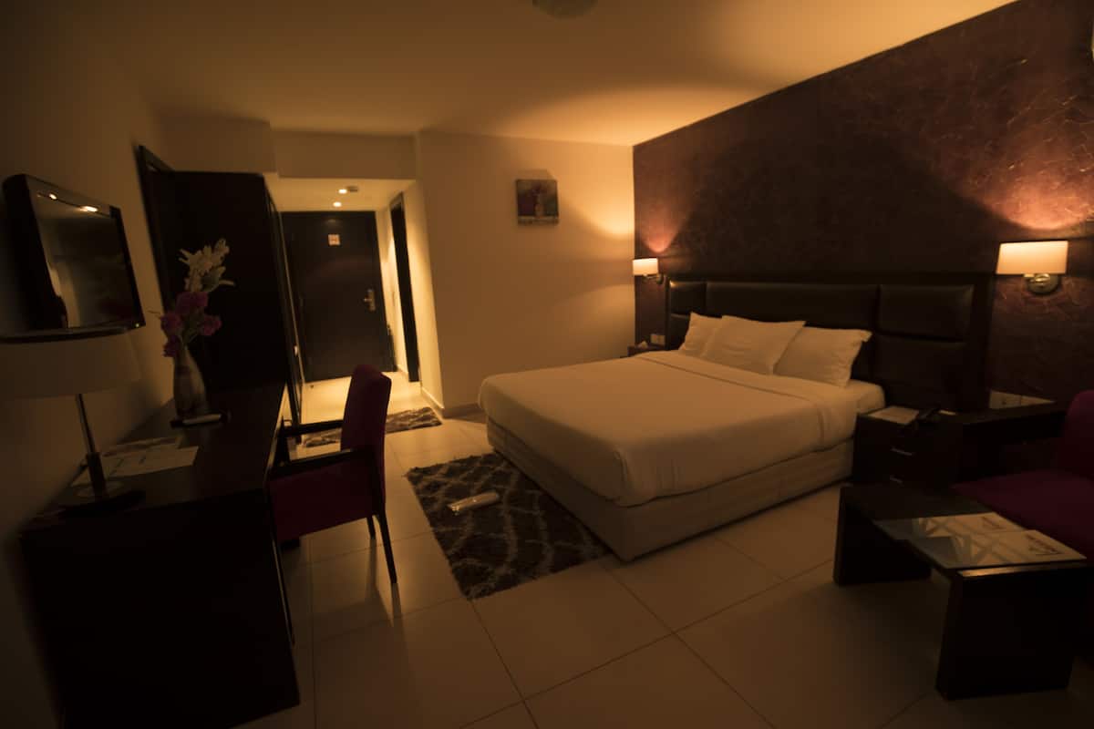 Una habitación de hotel con cama, escritorio, silla y mesita de noche.