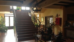 A staircase with a railing, a dining area with chairs and a table, and a wall with a red cabinet. - Hotel rural Llano Piña (Loja)