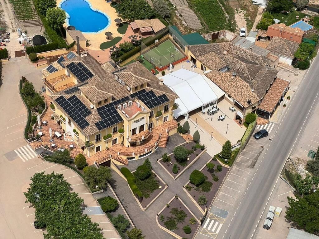 A large building with multiple floors, a swimming pool, and a tennis court.