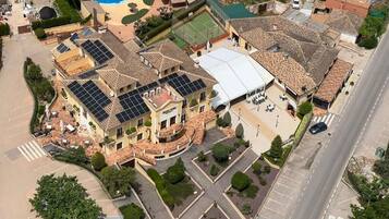 A large building with multiple floors, a swimming pool, and a tennis court.