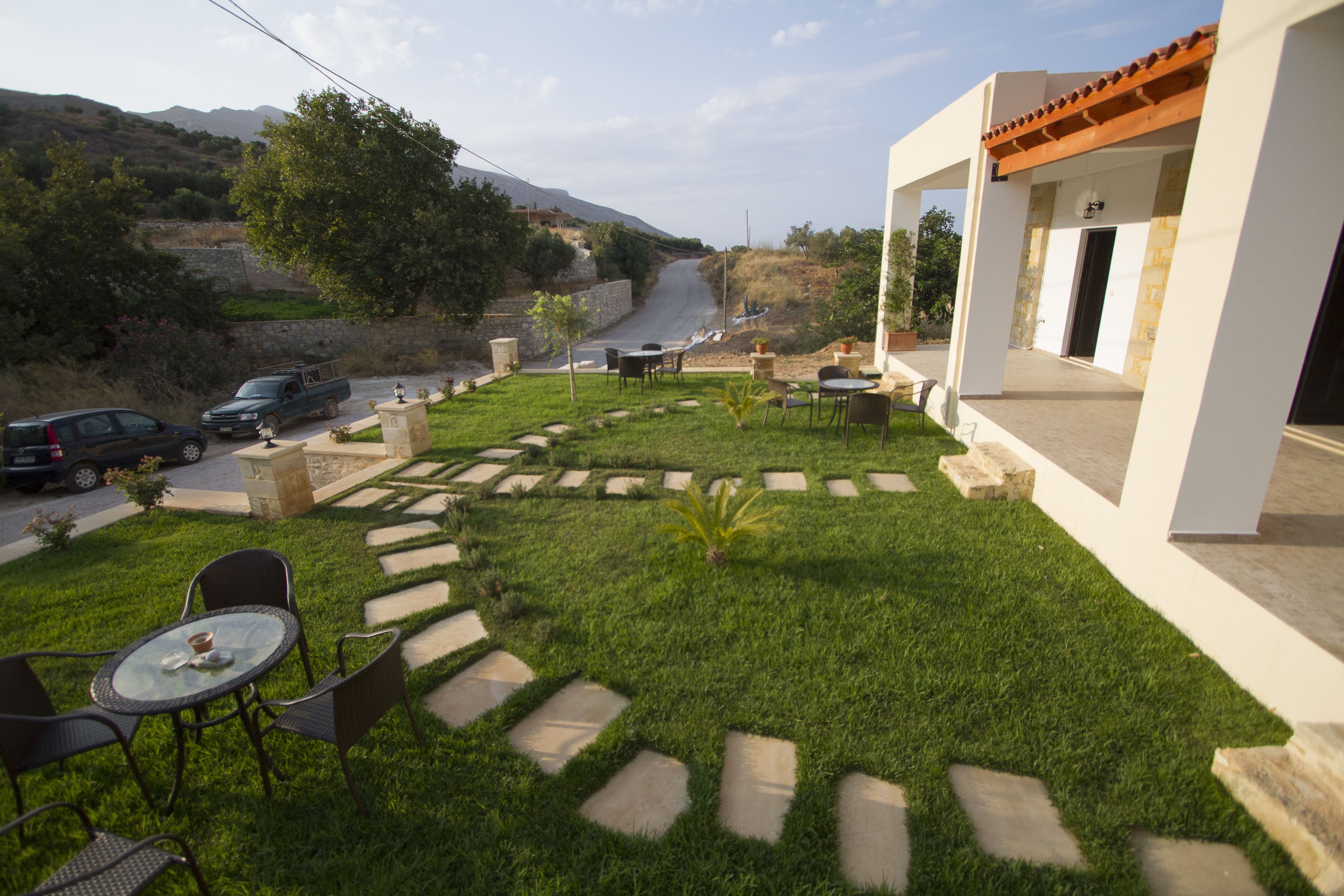 A patio area with outdoor seating, a stone pathway, and a view of a road and hills in the background.