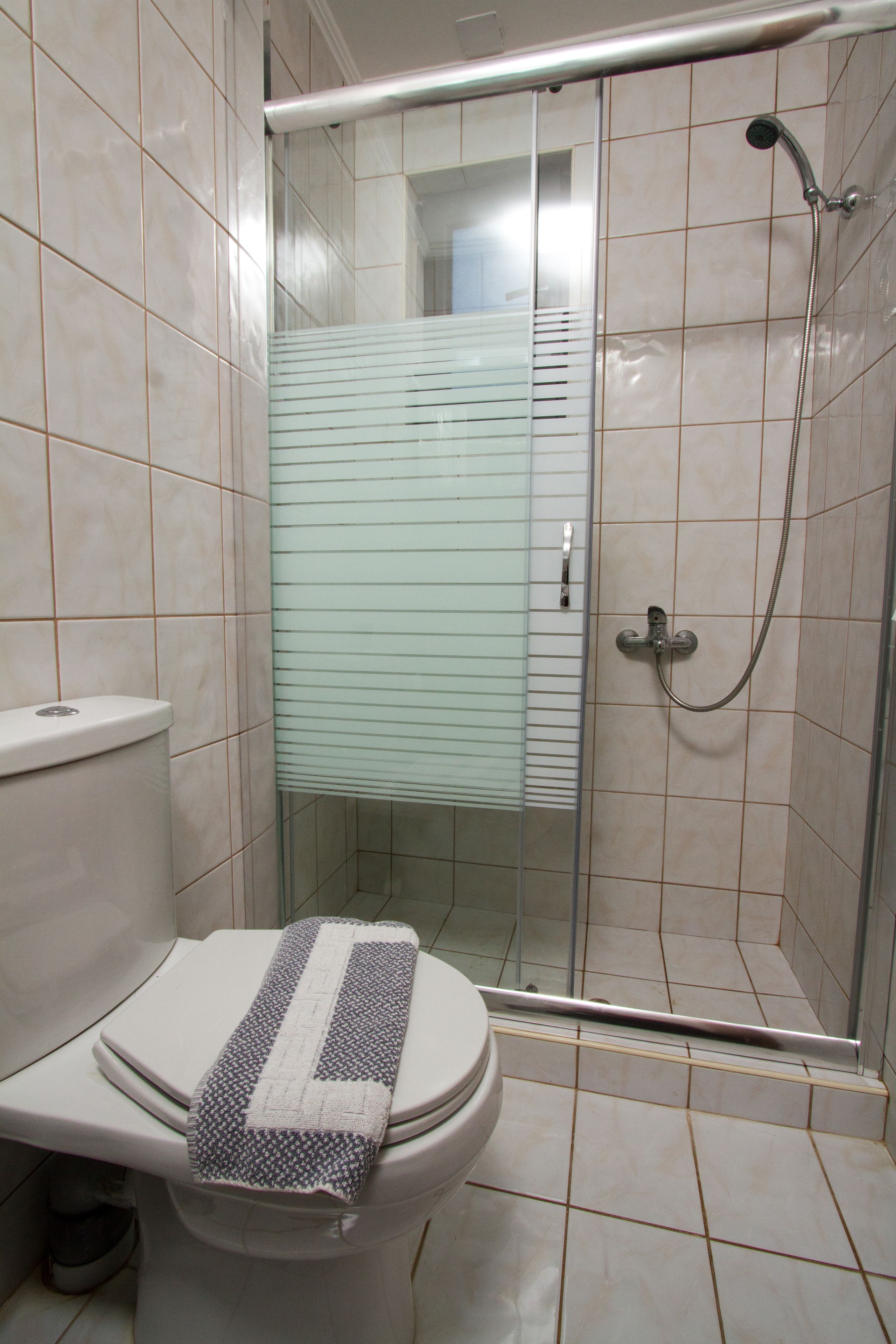 Un baño con inodoro, cabina de ducha y paredes con azulejos.