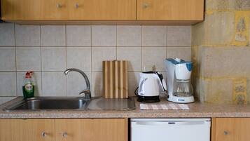 A kitchen with a sink, a cutting board, a coffee maker, and a dishwasher.