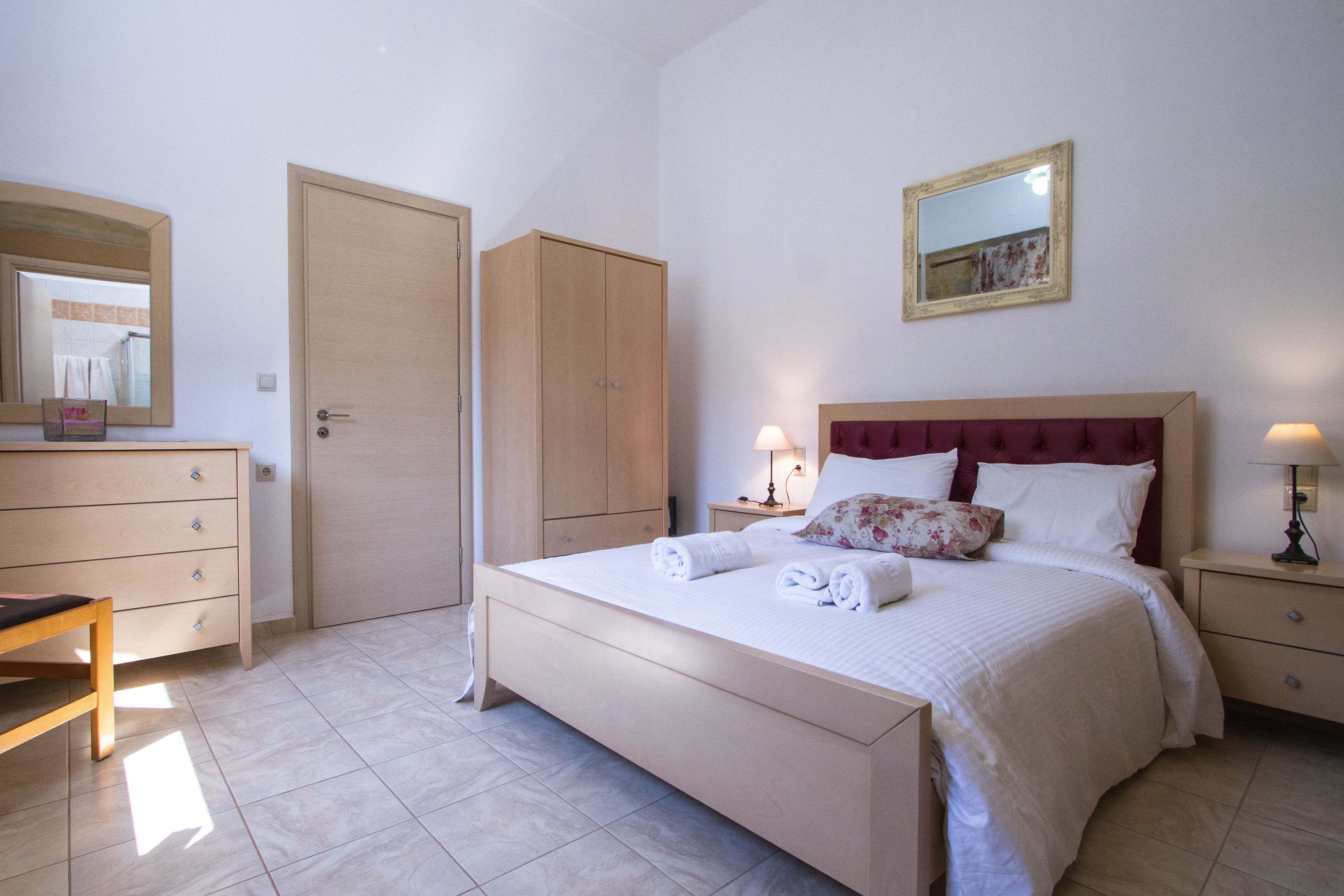 A bedroom with a bed, bedside tables, a wardrobe, a mirror, and a chair.