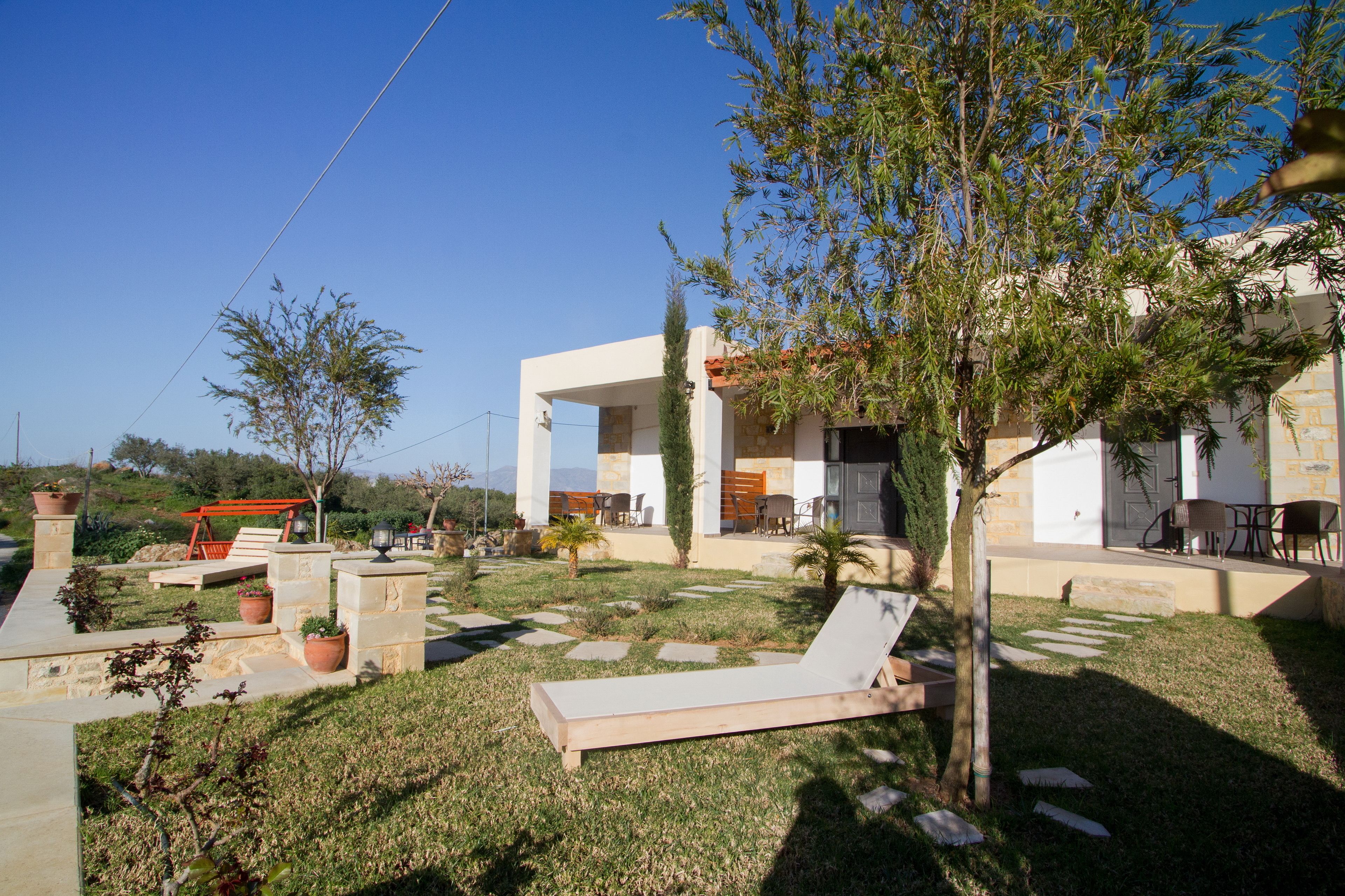 A modern outdoor area with a lounge chair, potted plants, and a patio table.
