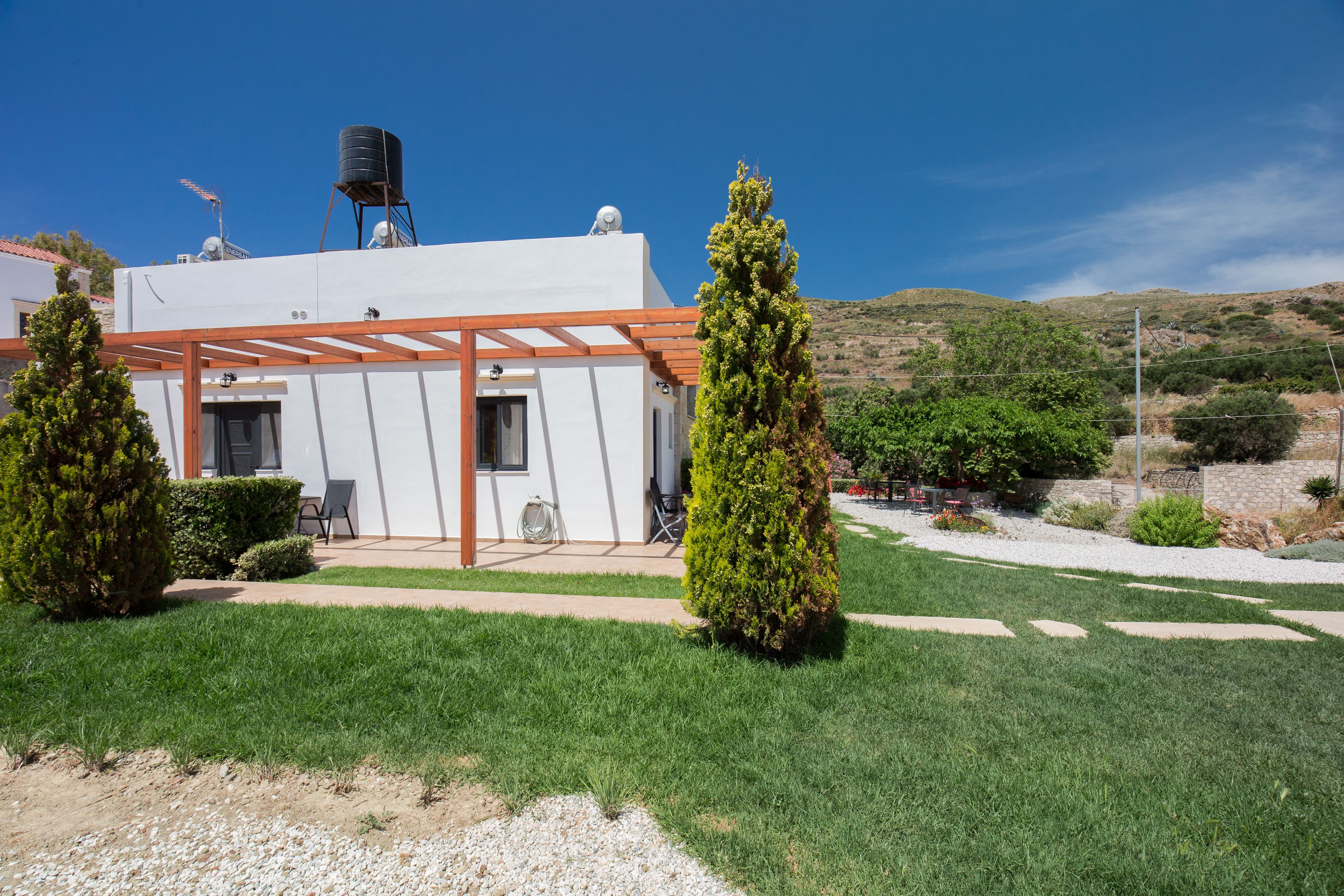 A modern house with a white exterior, a pergola, and a water tank on the roof.