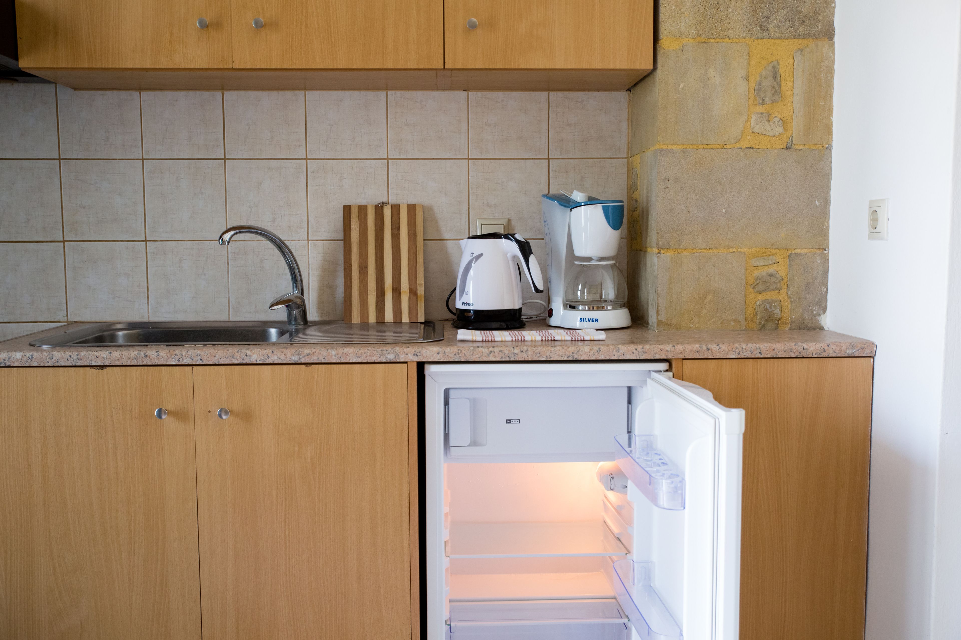 Una cocina con un refrigerador empotrado, una cafetera y un bloque de cuchillos sobre la encimera.