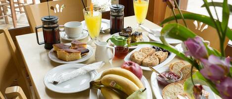 A breakfast table with various food items, including fruits, pastries, and beverages.