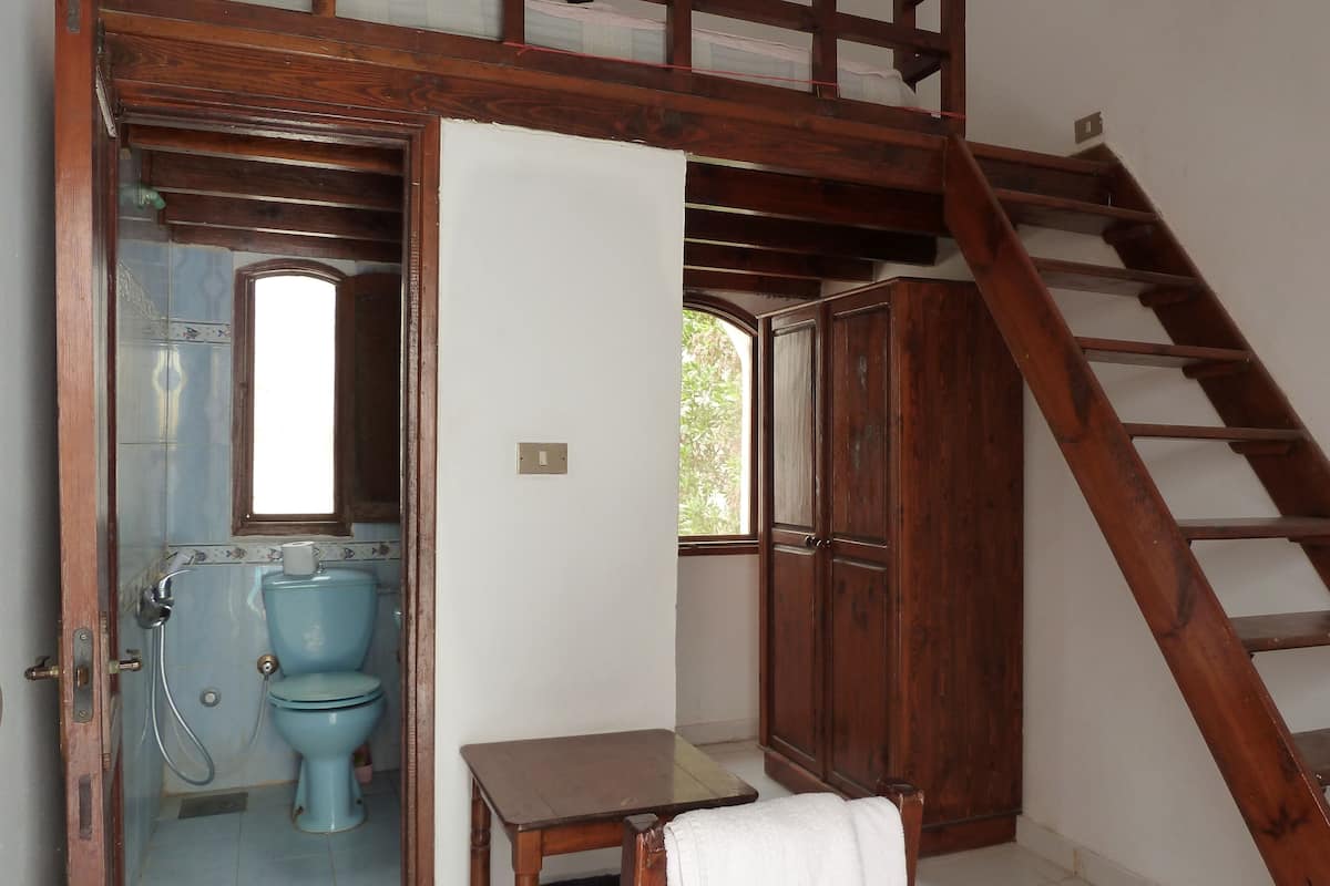 A room with a wooden staircase, a blue toilet, and a small table with a white towel.