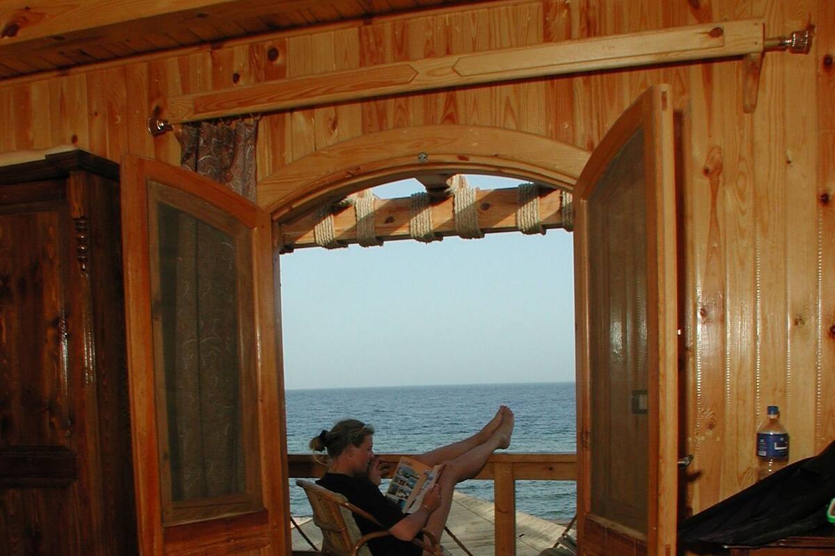 A wooden interior with a view of the ocean through an open doorway.