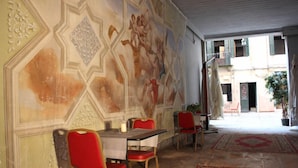 A dining area with a mural, red chairs, a table, and a patterned rug. - Residenza Della Spada (Venice)