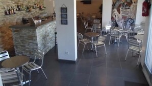 A restaurant with a stone wall bar area, metal chairs, and tables. - Hôtel Résidence U Nebbiu (Olmeta-di-Tuda)
