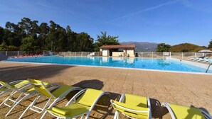 A swimming pool with yellow chairs and a small building, surrounded by trees and hills. - Hôtel Résidence U Nebbiu (Olmeta-di-Tuda)