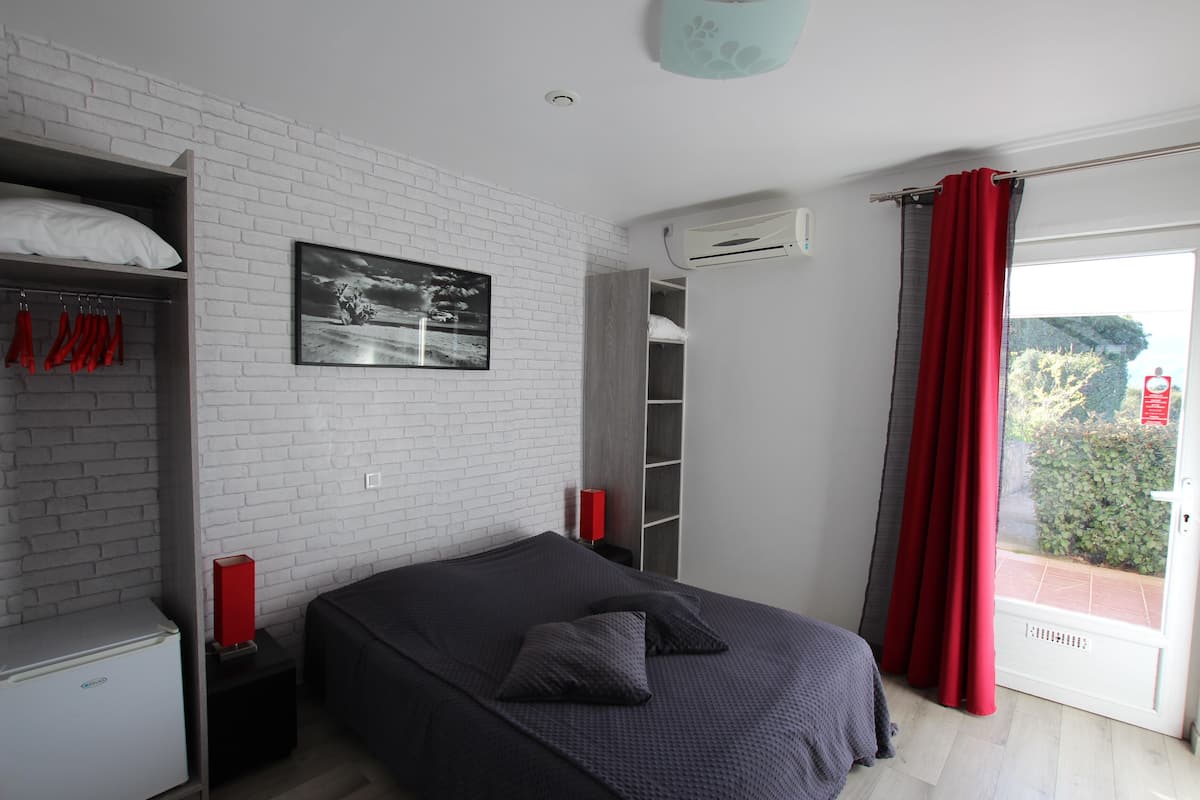 Une chambre à coucher avec un lit, une armoire, une lampe rouge et une fenêtre avec un rideau rouge.