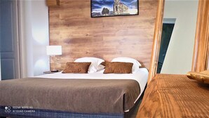 A hotel room with a bed, pillows, a bedside table, a lamp, and a wooden wall. - Hôtel Résidence U Nebbiu (Olmeta-di-Tuda)