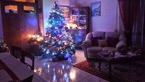 A living room with a Christmas tree, a sofa, a coffee table, and a cabinet. - B&B Il Ghiro - Country House (Mormanno)