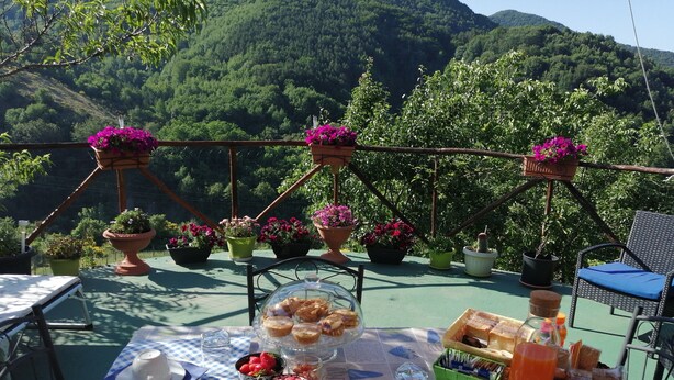 A table set outdoors with a view of lush green hills. - B&B Il Ghiro - Country House (Mormanno)