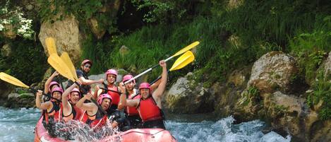 Un grupo de personas en una balsa roja navegando un río rodeado de rocas y vegetación.