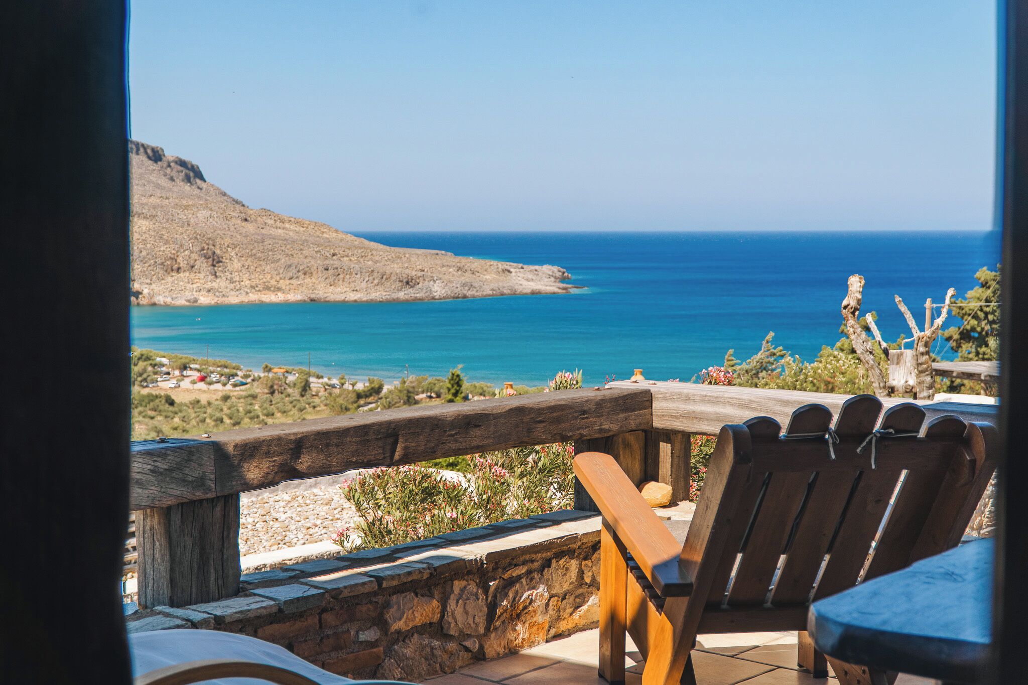 A wooden deck with a view of the sea and a mountain.
