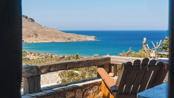 A wooden deck with a view of the sea and a mountain.