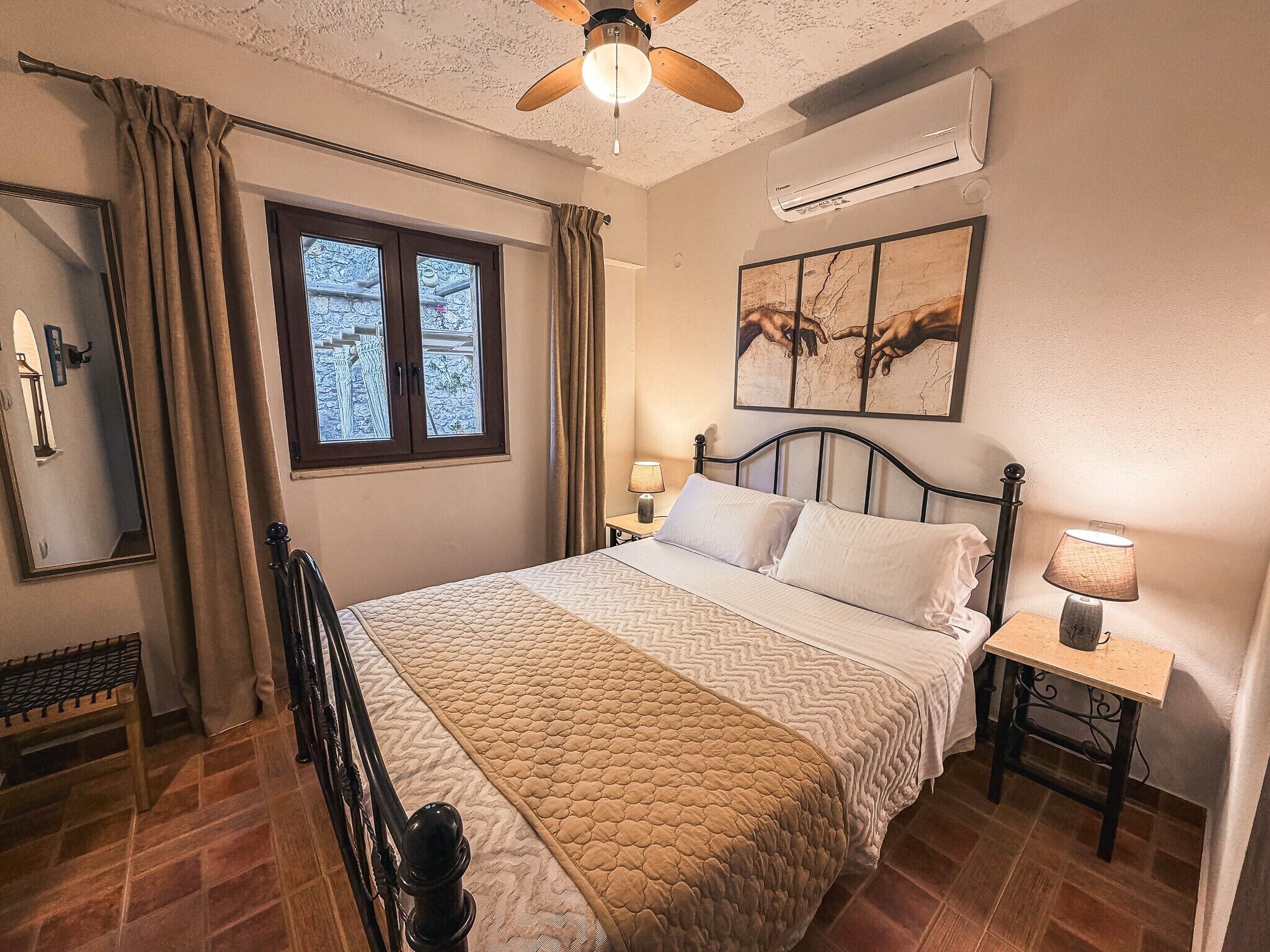 A bedroom with a bed, a nightstand, a lamp, a ceiling fan, a window, and an air conditioning unit.