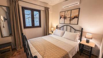 A bedroom with a bed, a nightstand, a lamp, a ceiling fan, a window, and an air conditioning unit.