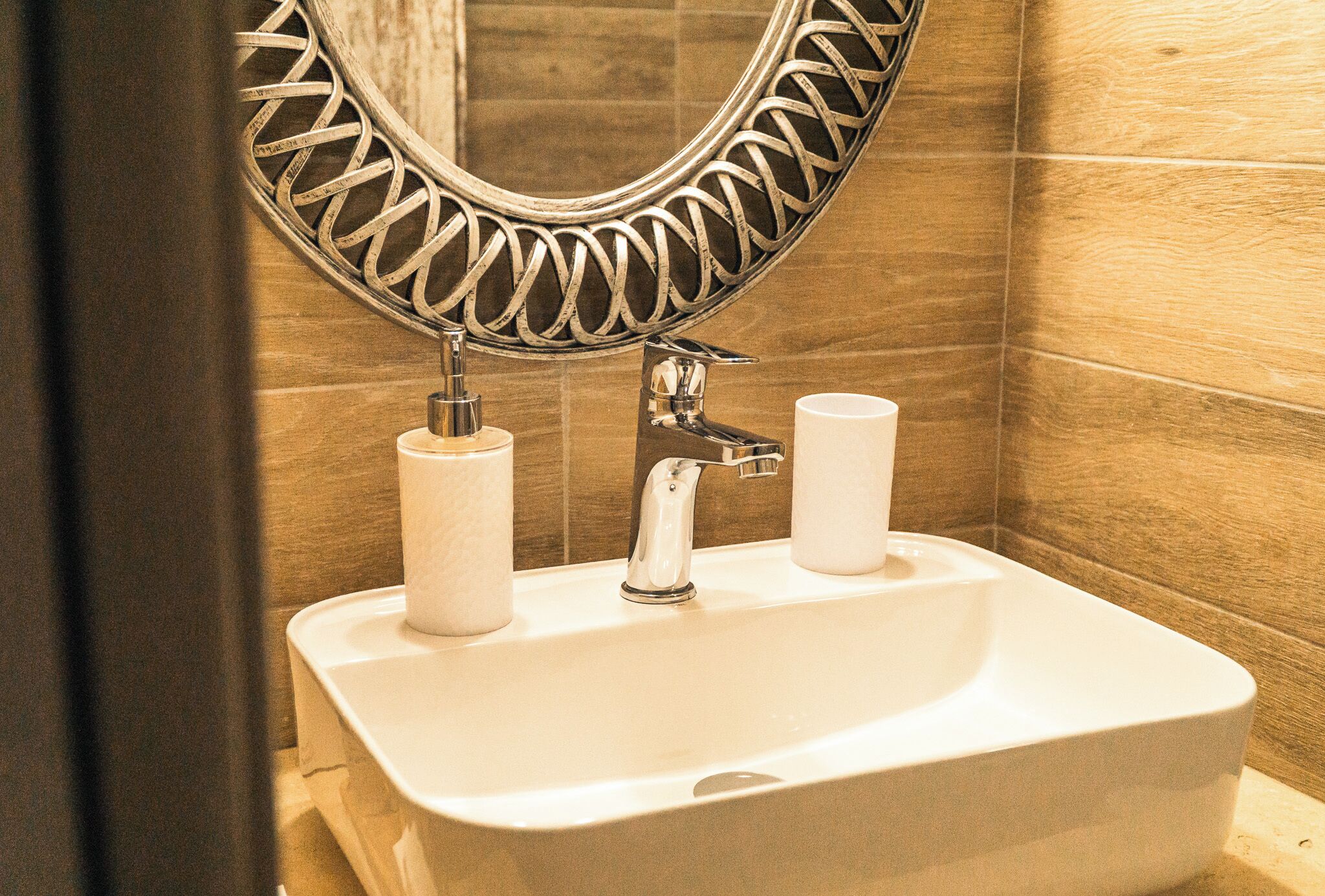 A bathroom sink with a mirror, two paper towel dispensers, and a faucet.