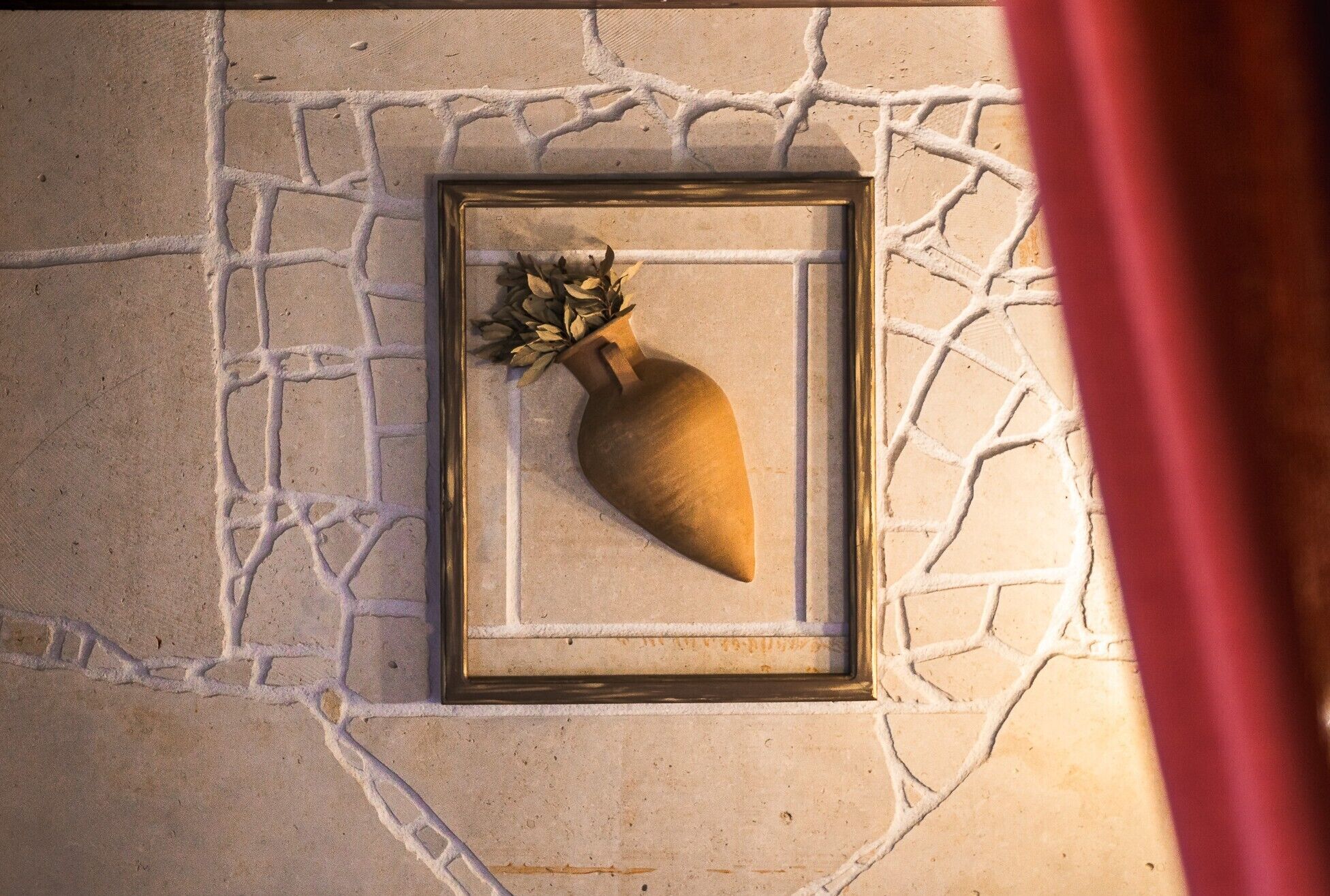 Un objeto enmarcado con un adorno de hoja sobre una pared con textura.